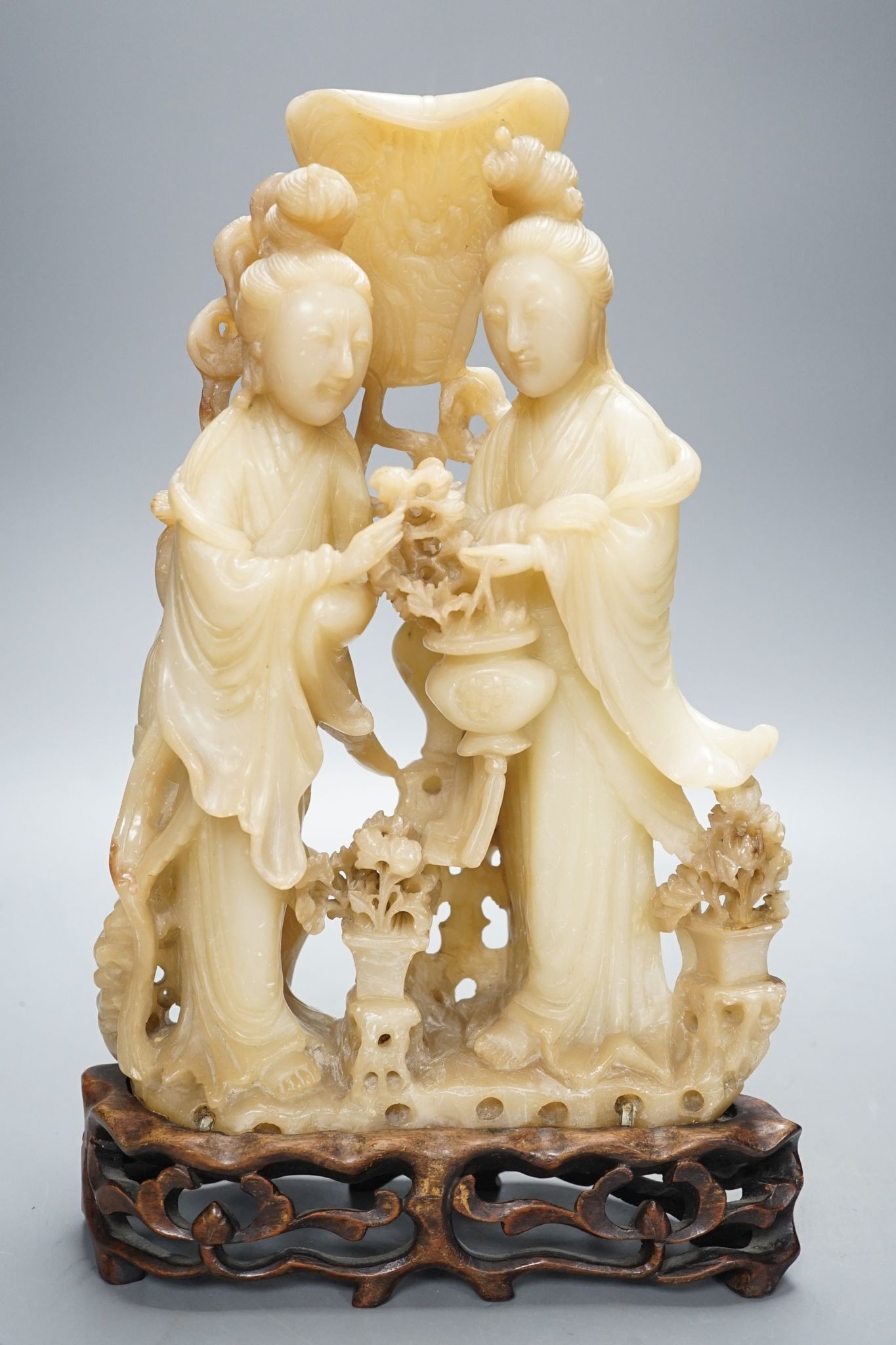 A Chinese soapstone carving of two ladies, wood stand, early 20th century, 36 cms high.